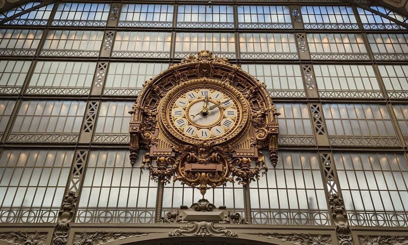 La grande horloge is large brass colored clock fixed to steel and glass wall.