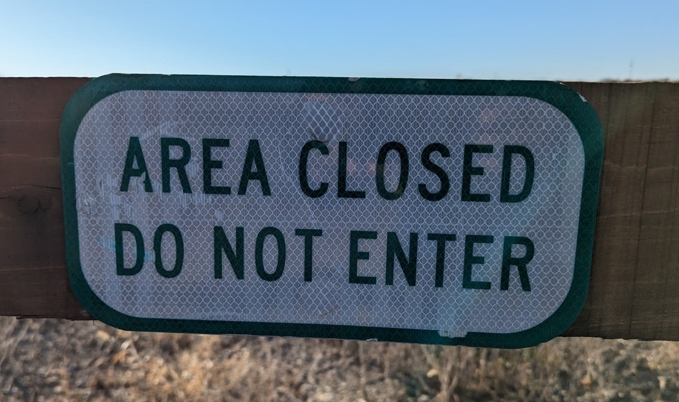 A weathered sign mounted on a wooden beam reads 