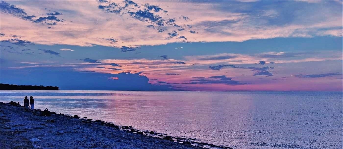 Sunset over Lake Ontario a couple of people are at the waters edge