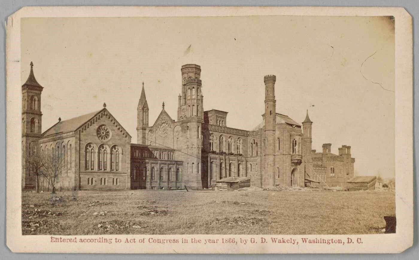 This carte-de-visite depicts the Smithsonian Castle building photographed showing a southwest view. The building is surrounded by rocky and grassy soil with one small bare-branched tree in the left foreground.